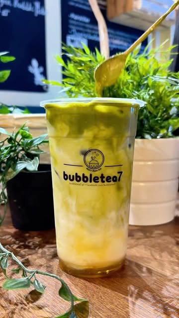Napój z matchą i mango w kubku Bubble Tea 7, obok roślina